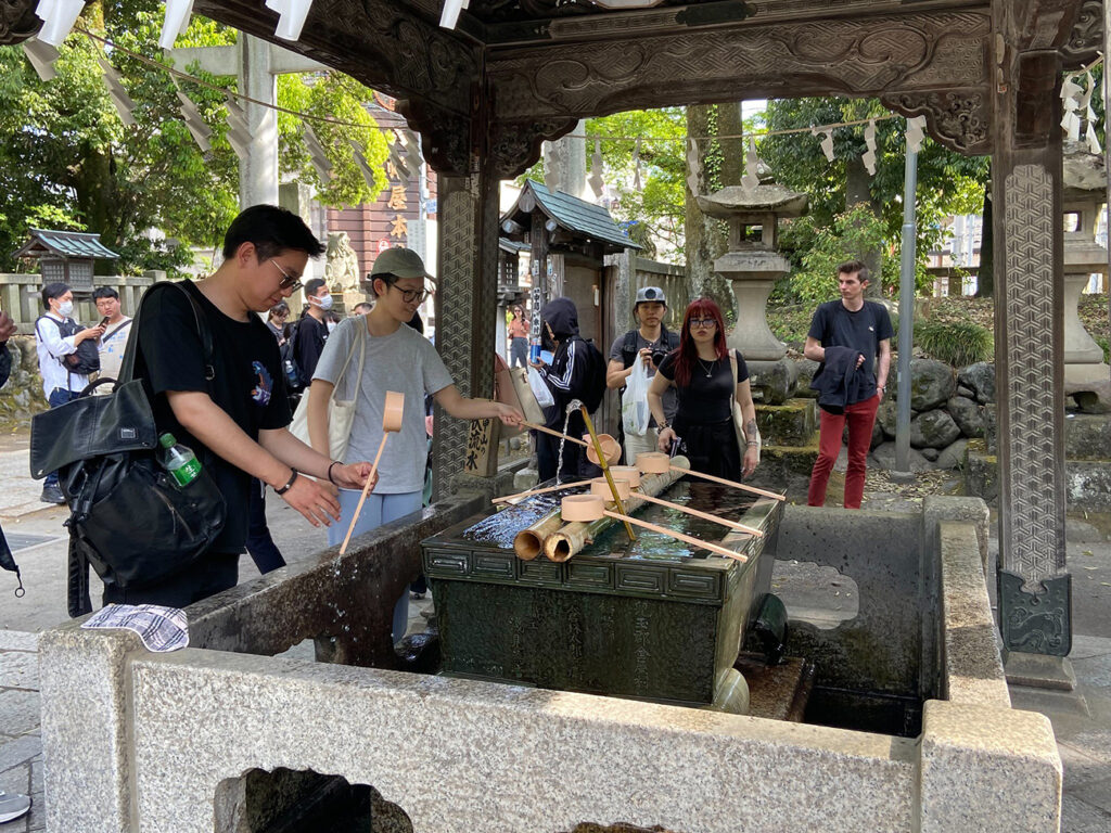 KCP students participating in a purification ritual where they wash their hands to cleanse themselves prior to entering the shrine