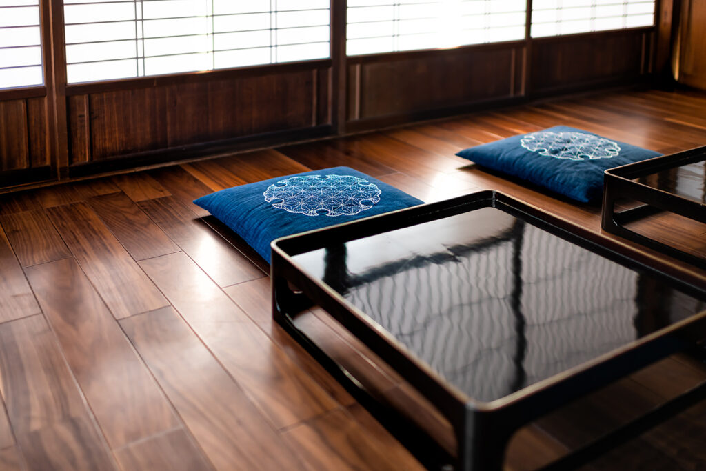 Traditional japanese machiya house or ryokan restaurant with black lacquered wooden table, cushion pillows and sliding paper doors with natural bright light