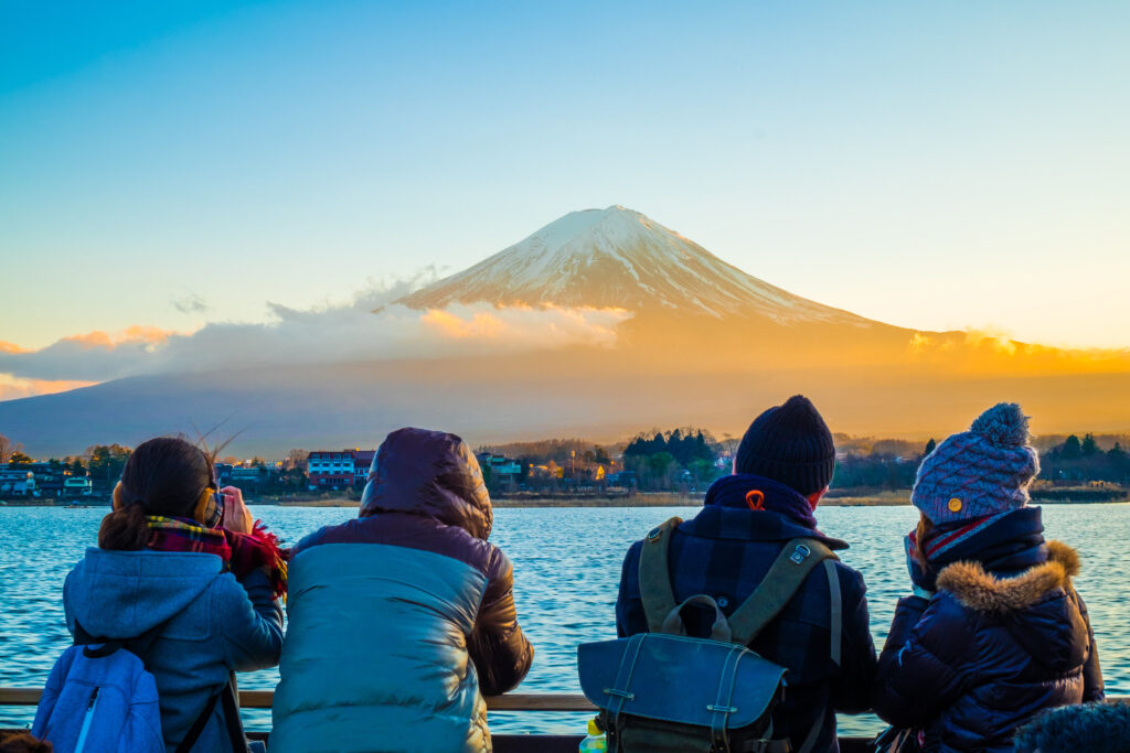 Tourists enjoy freely view Mt.Fuji Beautiful sunset from the pleasure boat on the water are wonderful of Lake Kawaguchiko in winter , Japan